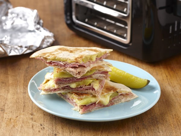 Stack of cuban quesadillas on a blue plate with a pickle