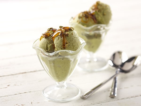 Glasses filled with avocado-pistachio frozen yogurt and garnished with drizzled honey and chopped pistachios