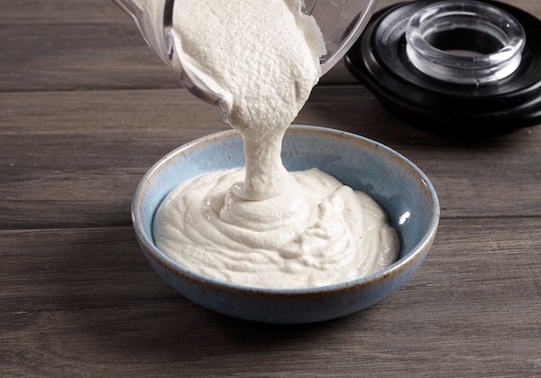 vegan cashew cheese in a blender, being poured into a bowl
