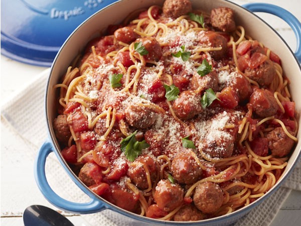 Spaghetti and meatballs in Dutch oven topped with cheese and fresh parsley