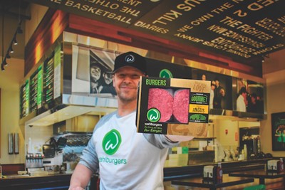 Donnie Wahlberg holding up a package of Wahlburgers at Home Angus beef patties.