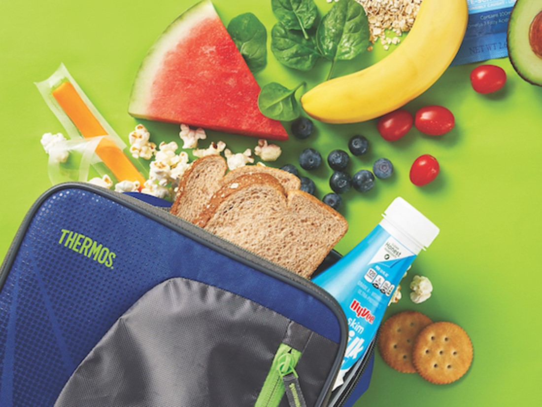 Lunchbox with whole grain bread, milk, cheese, fruit, avocado, and crackers
