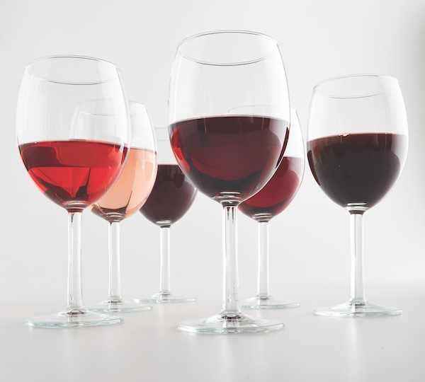 six wine glasses with different types of red wine