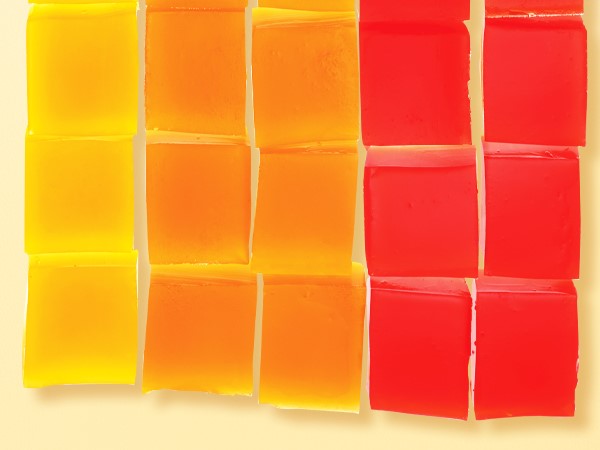 Yellow, orange, and red gelatin cubes organized in a grid on a light yellow background. 