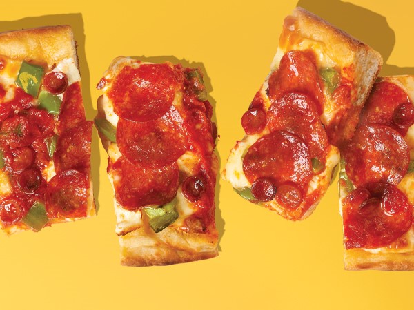 4 rectangle slices of Detroit-style pepperoni pizza on a yellow background. 