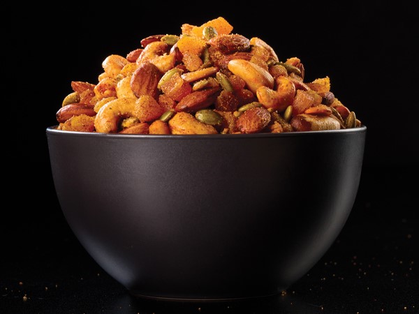 A bowl of mixed nuts in a black bowl on a black background.
