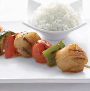 Grilled scallops on a skewer with green bell peppers, cherry tomatoes, and a side of white rice