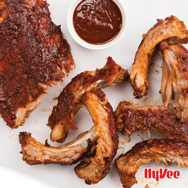 BBQ ribs on parchment paper with a side dish of BBQ sauce