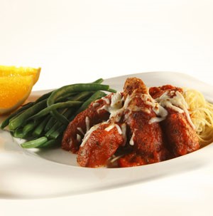 Platter of Chicken Parmesan over a bed of pasta with a side of Green Beans