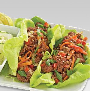 Lettuce wraps filled with ground meet and topped with shredded carrots, chopped bell peppers, and sliced green onions