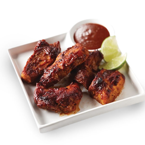 Country-style ribs on a plate with barbecue sauce and lime wedges