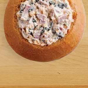 Bread bowl filled with baked ham and cheese dip