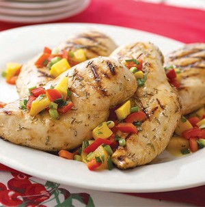 Grilled chicken on white plate and topped with diced mangoes, peppers, and peaches