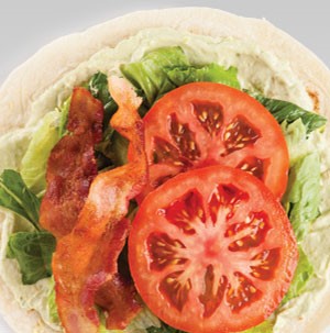 Tortilla wrap filled with avocado spread, bacon, lettuce and tomato