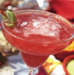 Martini glass filled with non-alcoholic pomegranate margarita with a lime wedge