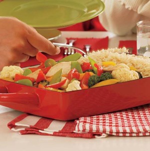 Red casserole pan filled with mixed vegetables, rice, and chicken