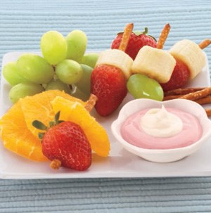 Mixed fruit kabobs made from pretzel sticks with fruit dip on the side