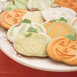 Plate of pumpkin-decorated cookies in green, white and orange icing