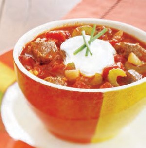 Bowl of beef chili el paso garnished with sour cream and green onion