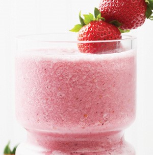 Glass filled with a pink berry smoothie, garnished with whole strawberries