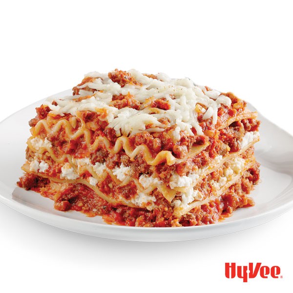 Lasagna with layers of cheese, red sauce and meat, topped with shredded cheese