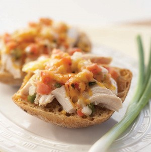 Shredded chicken topped with cheese and tomatoes and a green onion on the side