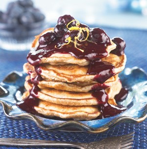 Stack of blueberry-flax pancakes topped with blueberry sauce on a blue plate