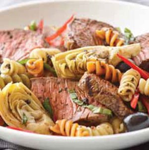 Plate filled with beef, pasta and artichokes and tossed in a balsamic vinaigrette