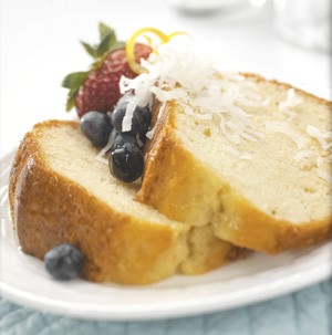 Tow slices of stacked angel food cake garnished with fresh berries, lemon zest, and shredded coconut