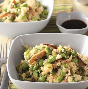 Couscous with edamame and sliced mushrooms in a white square bowl