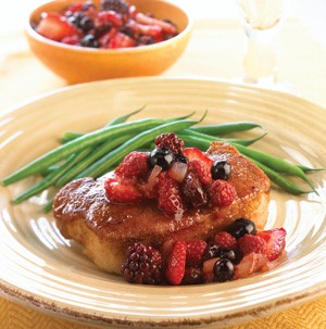 Bowl of pork chop topped with berry salsa and fresh green beans