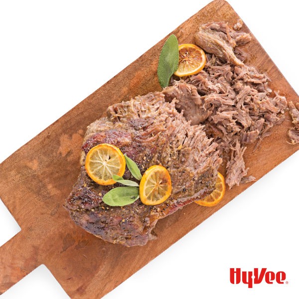 Pork shoulder topped with sage and oranges with shredded meat on the side
