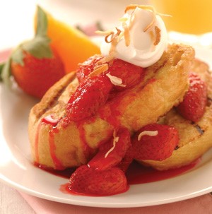 French toast topped with strawberries, whipped cream and toasted coconut shreds 