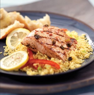 Rice topped with grilled mahi mahi fillet, sliced lemons, and sliced red bell peppers