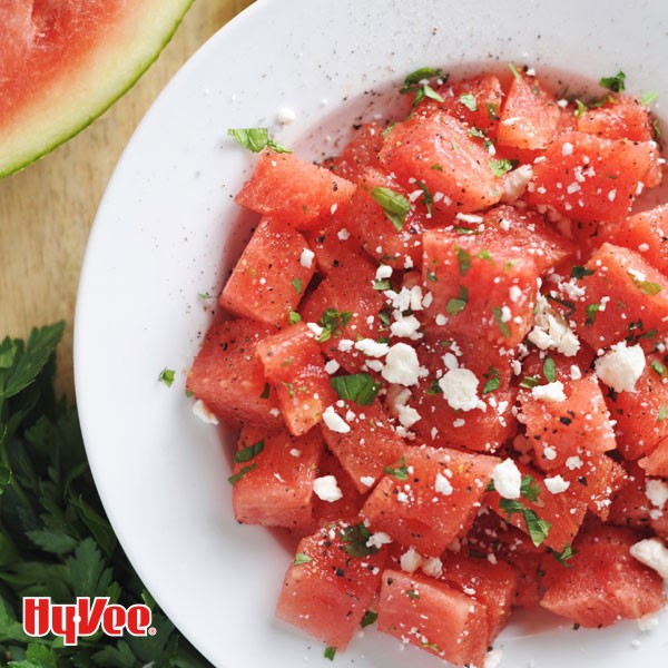 Cubed watermelon topped with crumbled cheese, black pepper, and parsley
