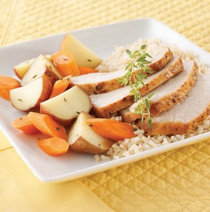 Plate of pork roast served with carrots, potatoes and rice