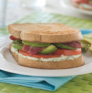 Bacon, tomato, avocado and basil-lime mayo sandwiched between two whole grain bread slices