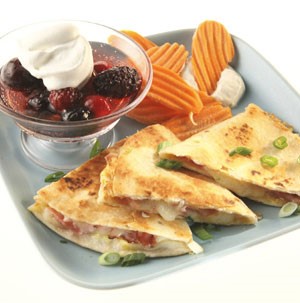 Blue plate topped with triangle-cut quesadillas, crinkle chips and mixed berries on the side