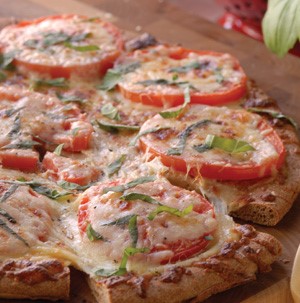Pizza topped with sliced tomatoes, cheese, and chopped basil