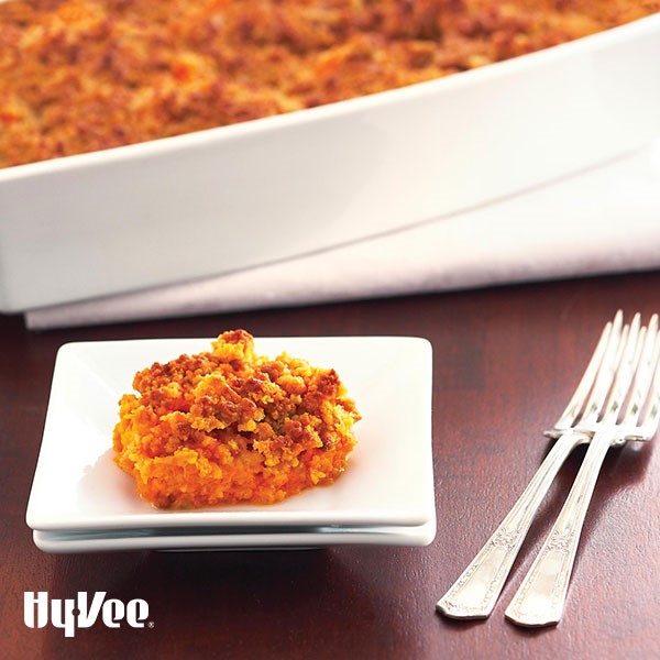 Small plate filled with baked mashed sweet potatoes layered with a crumb topping next to silver forks