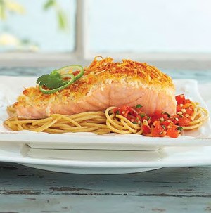 Parmesan-crusted salmon over red pepper salsa and angel hair pasta on a white plate