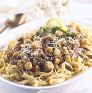 Platter of fettuccine noodles topped with scallops, mushrooms, bell pepper, pesto sauce and parmesan