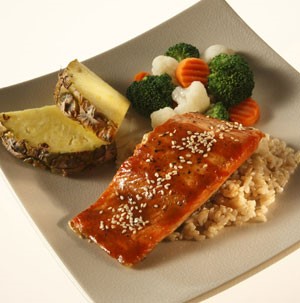 Plate topped with rice, glazed salmon, pineapple wedges, and mixed steamed vegetables