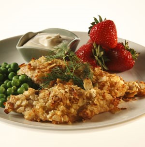 Tilapia covered in crunchy potato crust with peas and whole strawberries on the side