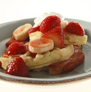 Waffles topped with sliced bananas and strawberries