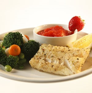 Plate of cod fillet with side of strawberry sauce and vegetables