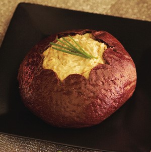 Bread bowl filled with hot french onion dip and garnished with fresh chives