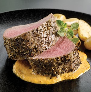 Spiced and sliced tenderloin on top of aioli garnished with fresh oregano leaves and halved baby potatoes