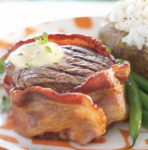 Bacon-wrapped fillet with melted butter and a side of green beans and baked potato