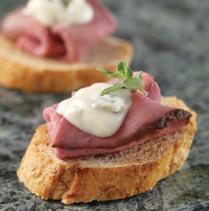 Sliced bread topped with roast beef and blue cheese sauce garnished with fresh thyme